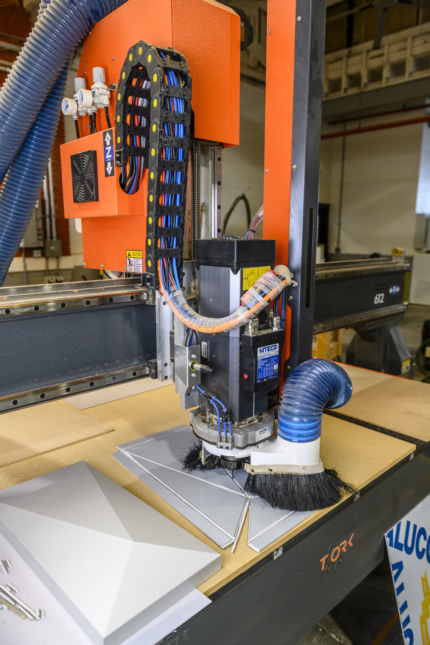 CNC router cutting grooves into a façade panel.