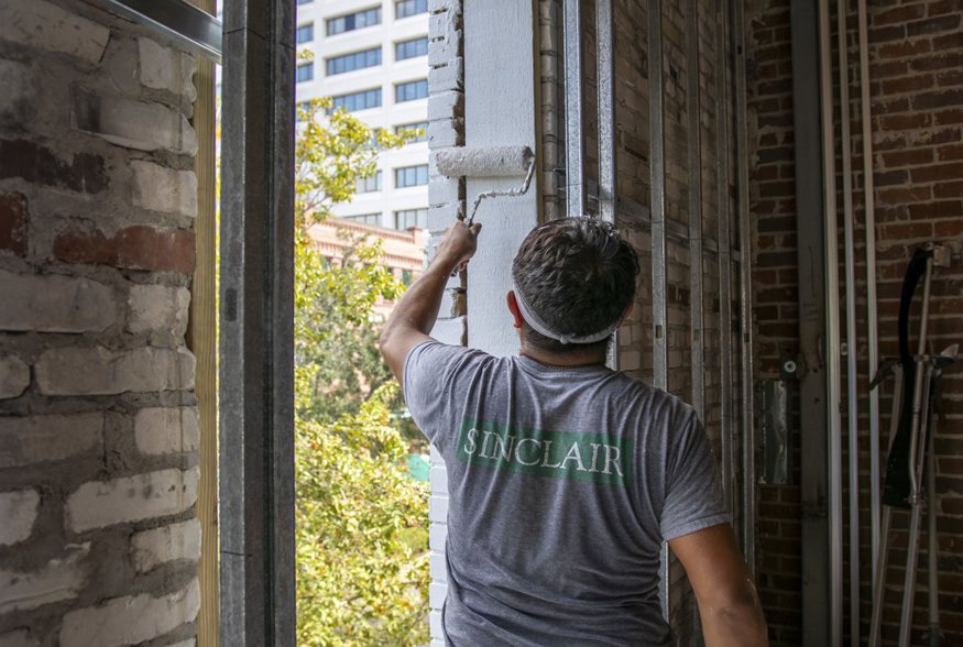Worker primes window opening with waterproofing paint.