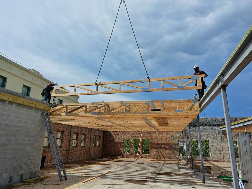 Worker positions truss with crane support.