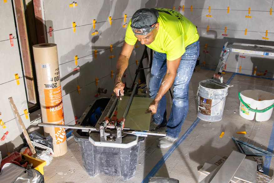 Worker cutting tile with manual tile cutter. 