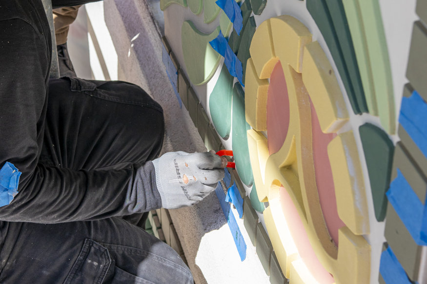 Craftsman aligns mosaic tile pieces within the recessed façade during installation.