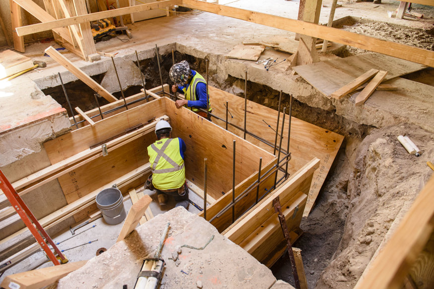 Construction workers finishing the elevator pit preparation in the historic bank building.