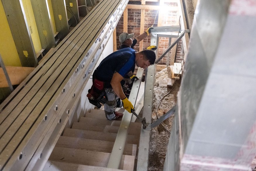 Crews install steel stair rail.