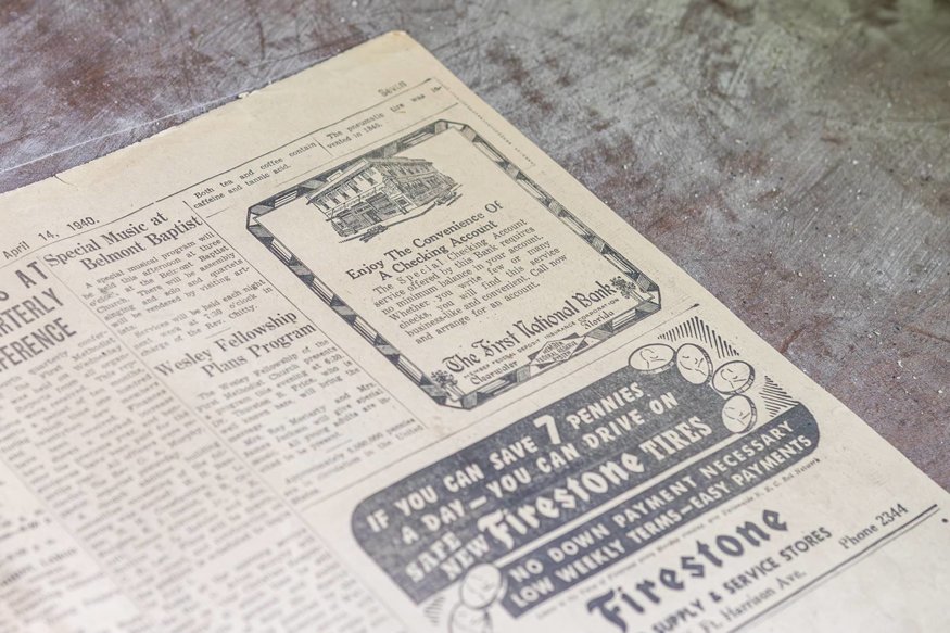 Close-up of newspaper clippings attached to a door with nails.