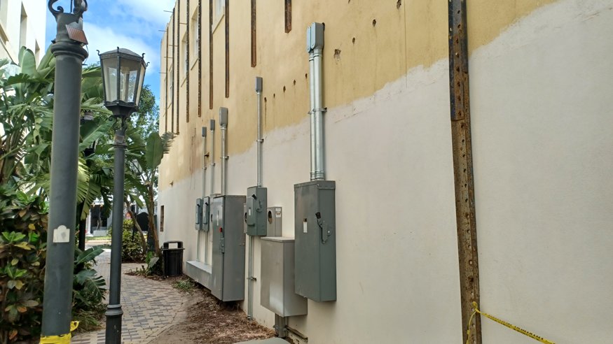 Electrical meters and panels are mounted on the exterior wall. 