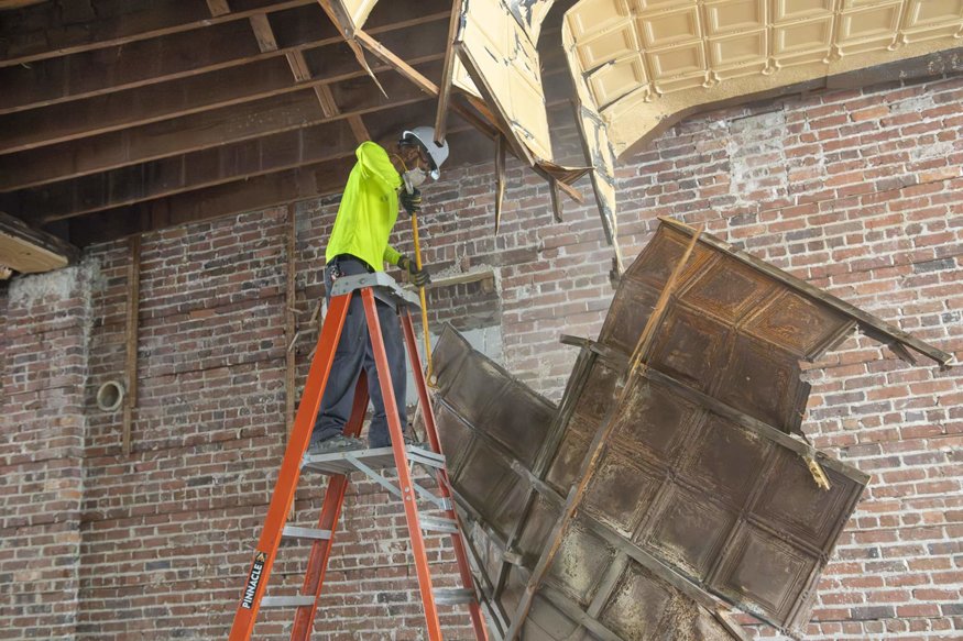 Ceiling panels falling away expose wood beams above.