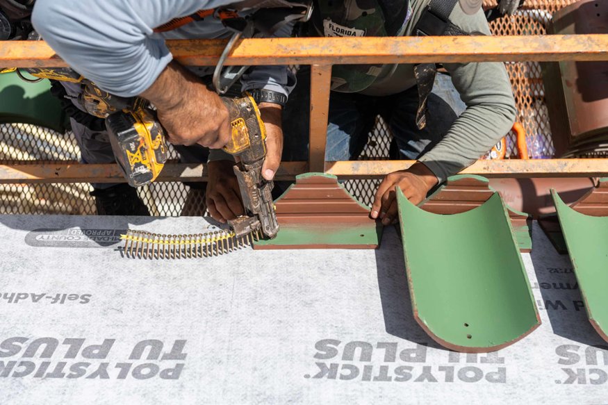 Close-up of nail gun fastening barrel roof tile.