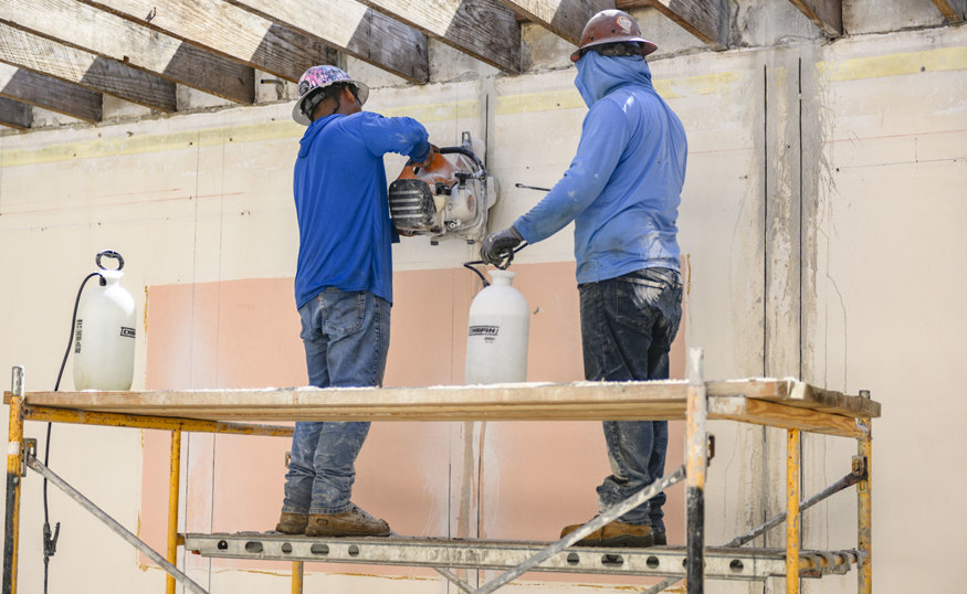 Workers cut reinforcement channels into existing walls.