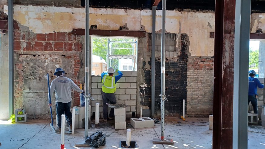 Construction workers installing concrete blocks to infill a historic back wall at the Woolworth building, preparing the area for stabilization.