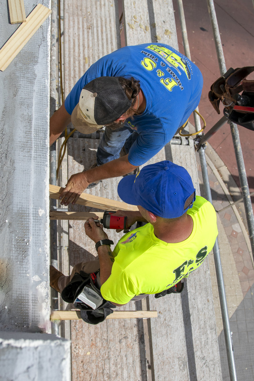 Crews install the roof framing to the wood ledger.