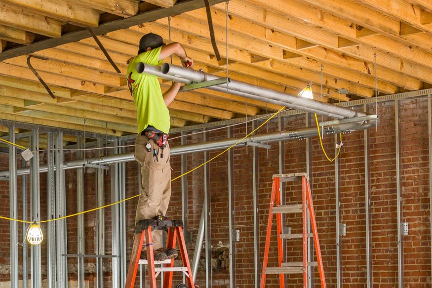 Worker attaches conduit to the second floor ceiling.