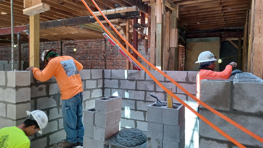 Workers prepare vertical steel rebar supports to reinforce the next level of the new elevator shaft.