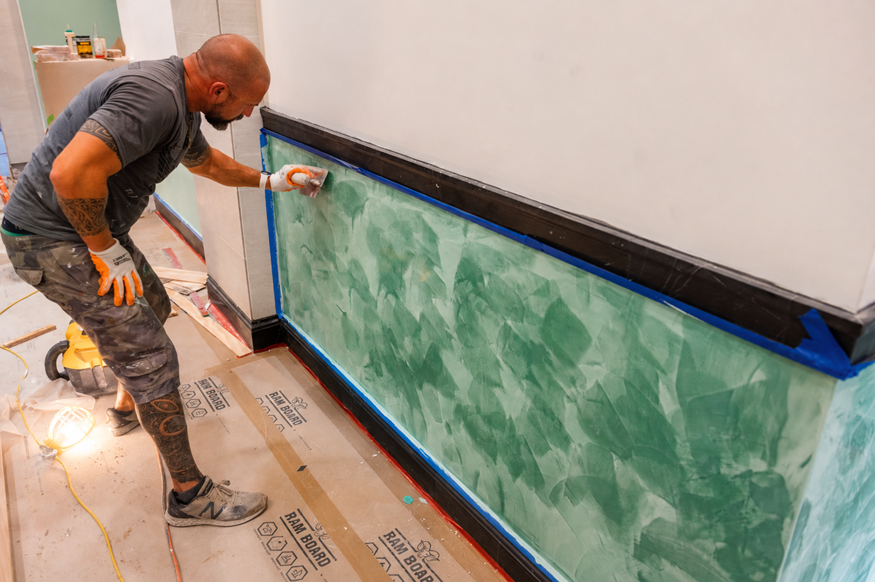 Worker spreads decorative plaster on wall. 