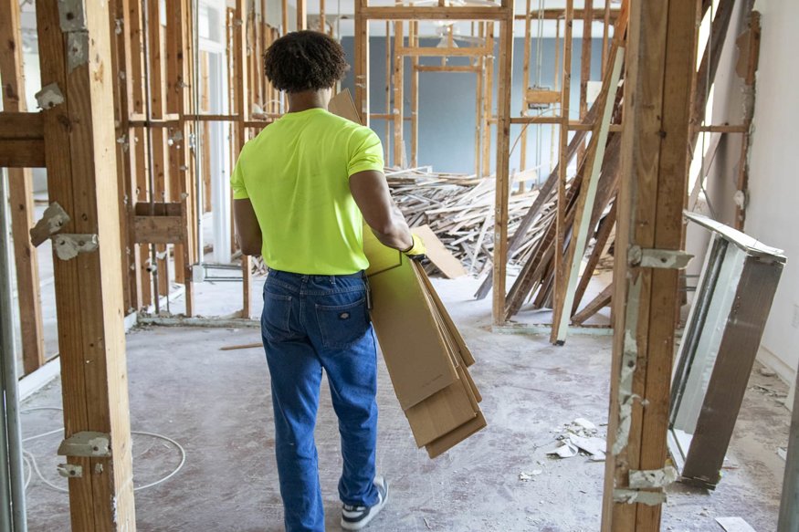 Worker carrying removed flooring panels.