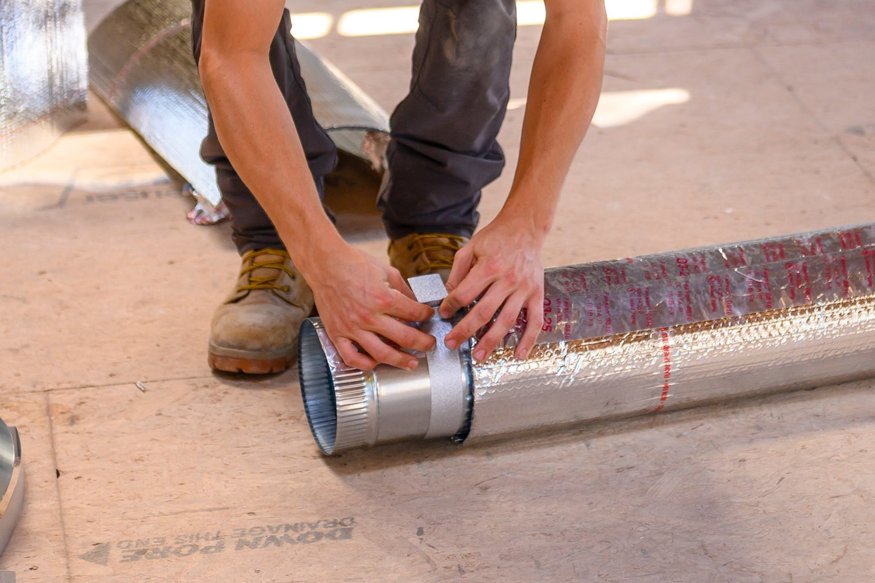 Worker preparing an air duct for installation.