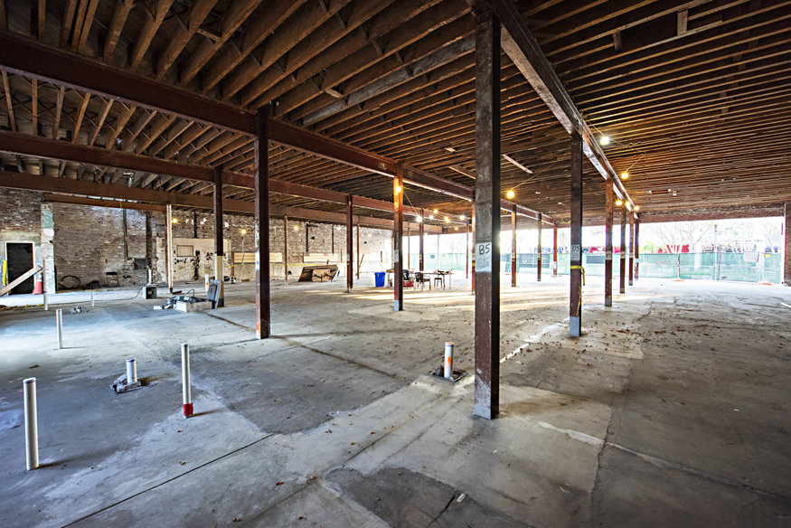 The interior of the Woolworth Building showing exposed steel columns and cleared concrete flooring, with visible signs of restoration work, including structural reinforcements and preparation for the next construction phase.