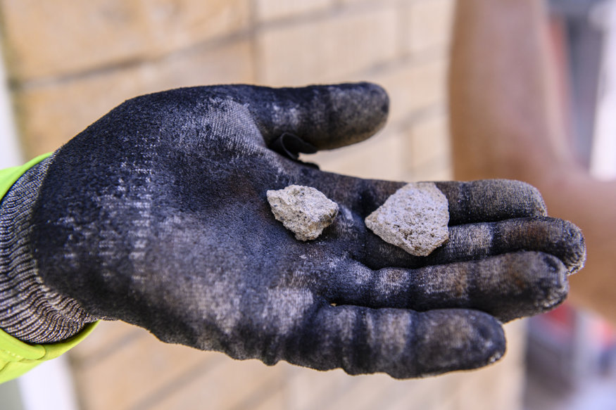 A crew member carefully removes a mortar sample from the Brown Brothers brick façade for laboratory testing to determine the historically appropriate mortar for repointing.