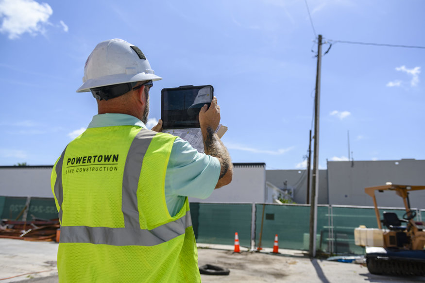 Contractor uses a tablet to inspect and document utility pole conditions behind the 600 Block.