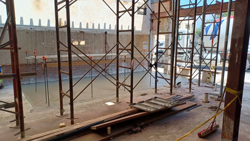 Fresh concrete poured into wooden forms for the new stairwell foundation.