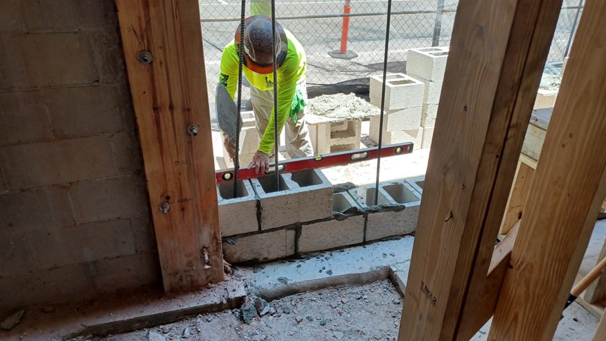 Restoration workers use levelling tools to align the newly built wall at the Peoples Bank site.