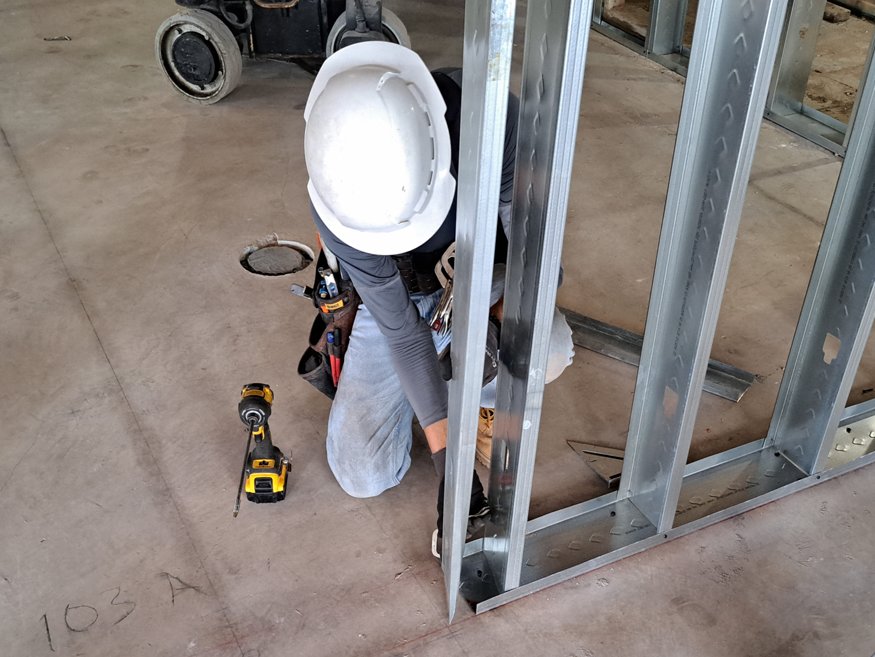 A crew member utilizing the layout to install the wall framing.