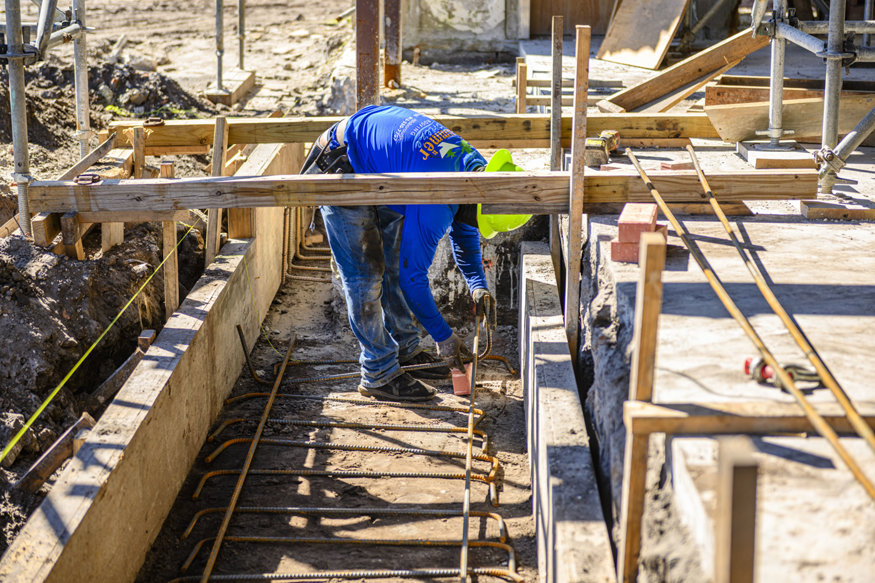 Worker positions reinforcing bars within new wall footing.