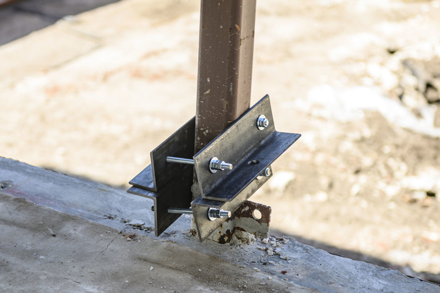 Bolted steel bracket secured around existing column.
