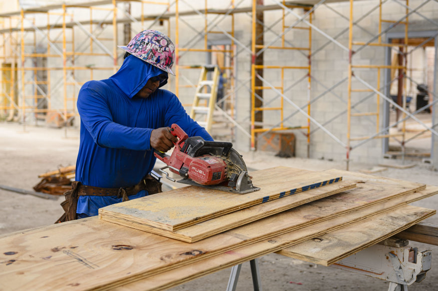 Worker cuts plywood panels with circular saw.