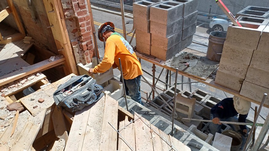 Wood boards installed by carpenters connect the roof framing to the newly rebuilt east wall.