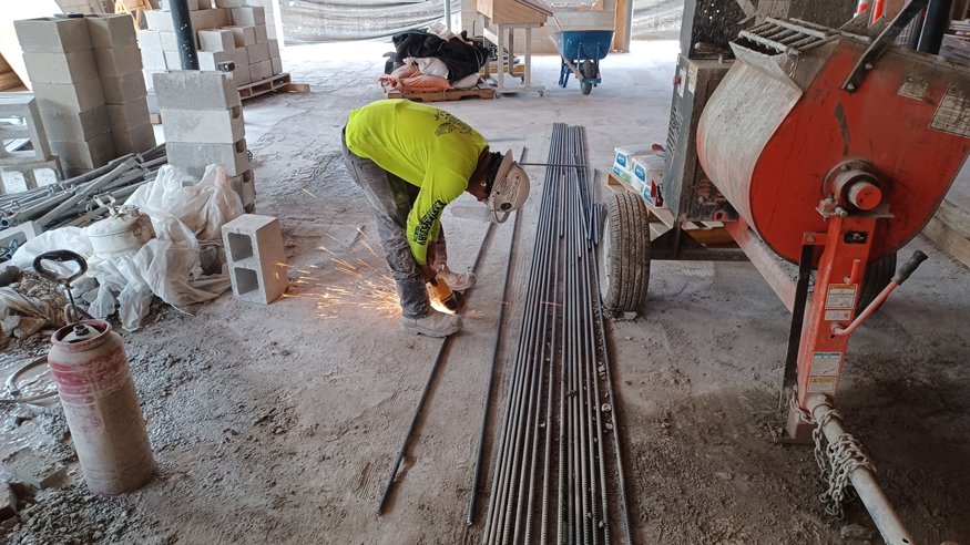 Worker cutting steel rods to fit into the wall.