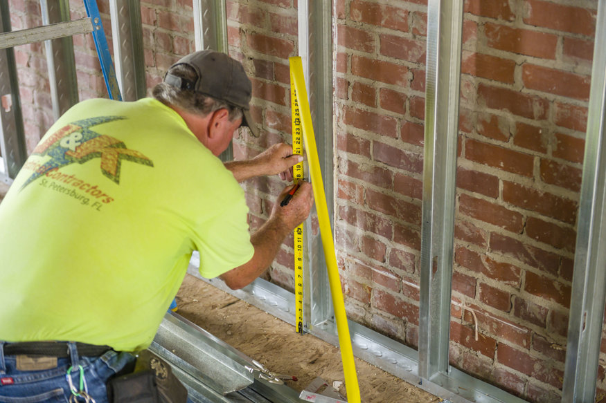  Worker measuring location for a bracket between framing studs.