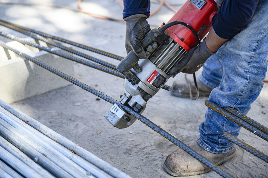 Crew member uses powered cutter to size reinforcing steel.