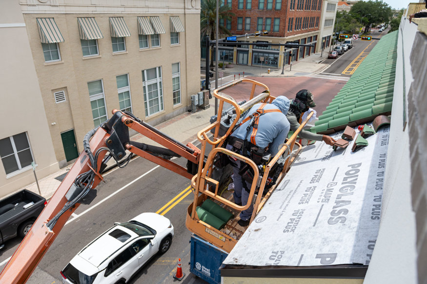 Fastening continues as tiles are secured over the underlying structure. 
