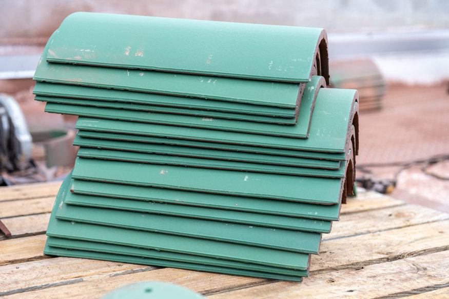 Green barrel roof tiles stacked and ready for placement
