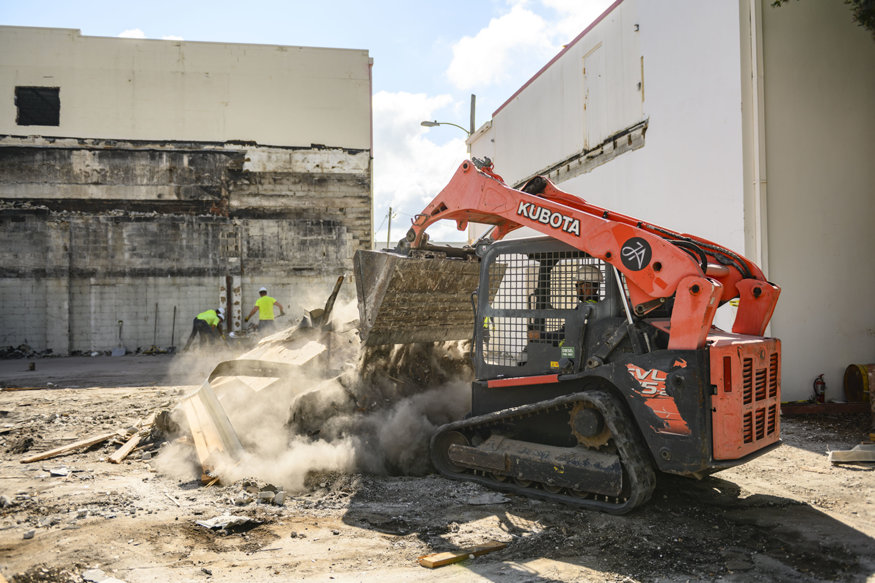 Demolition vehicle loader moves debris across cleared construction area. 