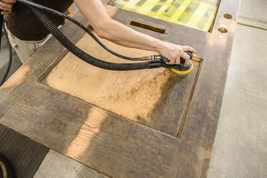 Historic door being sanded to reveal original wood grain.