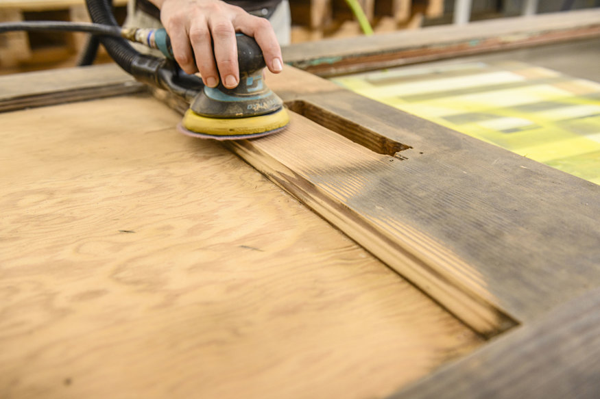 Close-up of sander revealing wood grain on historic door.