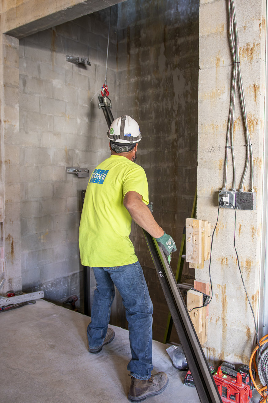 Workers assembling guide rails inside elevator shaft.
