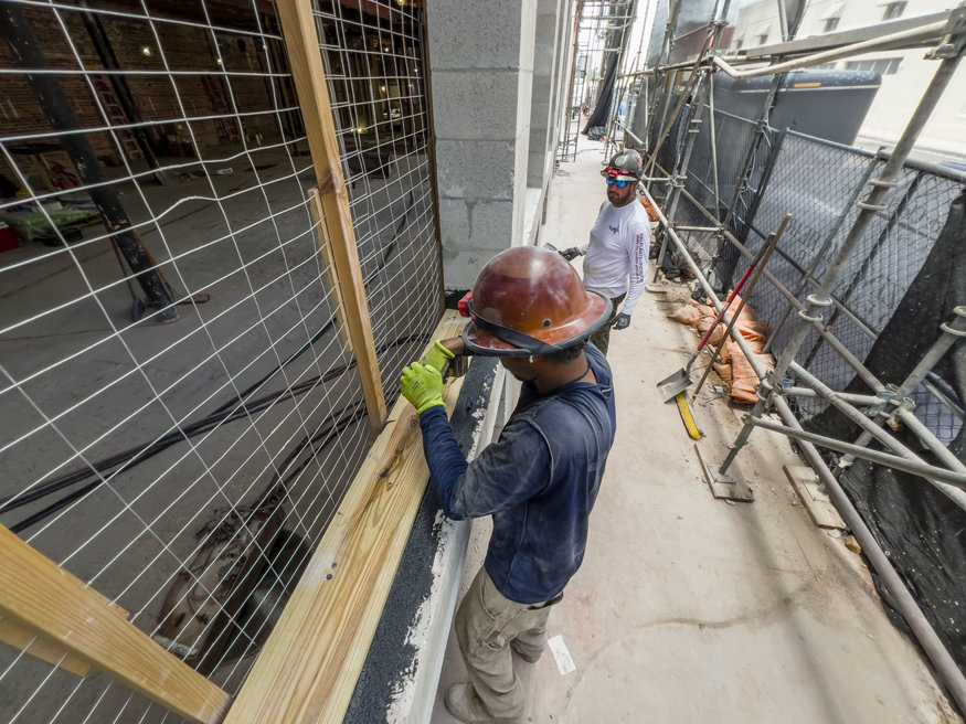 Two workers install and seal window bucks on exterior of Peoples Bank.