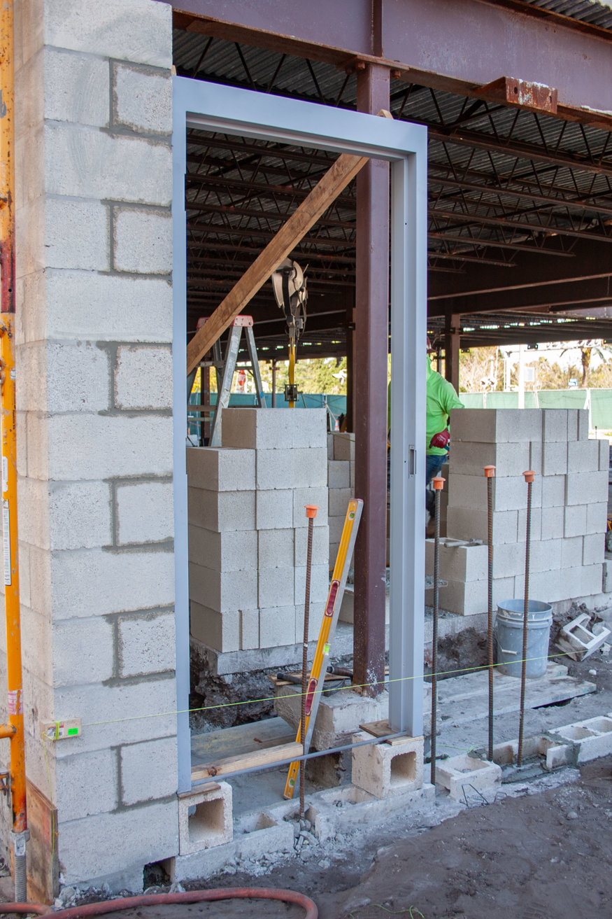 Mason builds CMU wall beside new door opening.