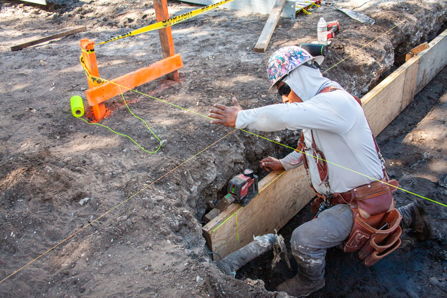Worker checks footing form alignment with laser level.