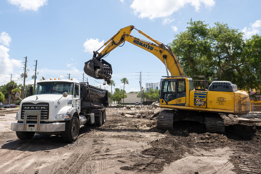 Excavator loads broken concrete into a truck. 