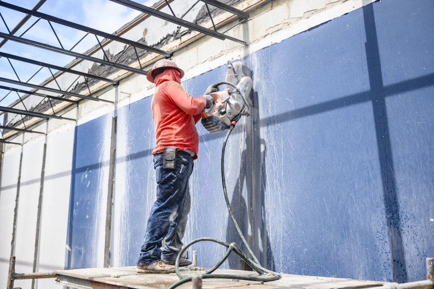 Worker saw cuts concrete masonry wall.