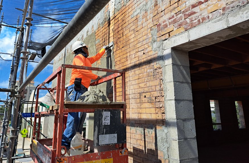 Worker applies new mortar layer to exterior brick at Peoples Bank.