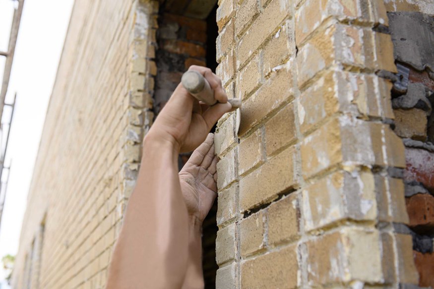 Fresh brick is installed around a window frame.