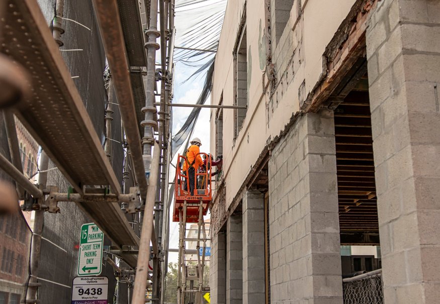 Jackhammers are used to remove thick stucco from facade.