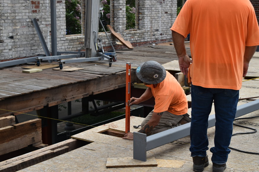 Worker uses level to check column placement near floor opening.