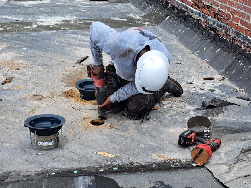 Worker installing the cast-iron drain pipes along ceiling.