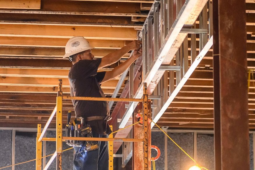 Framers install metal studs around beams.