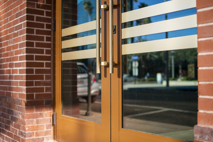 Close-up of the new storefront doors with brass handles and horizontal frosted glass accents, highlighting the façade restoration of the Telephone Building.
